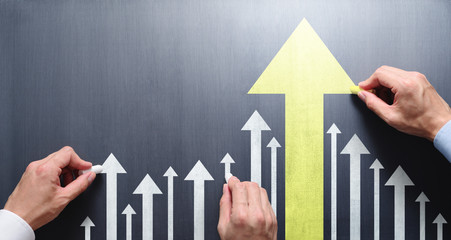 Business leadership and development concept. Businessmen drawing growth arrows on chalkboard.