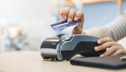 Customer using credit cart for payment to owner at cafe restaurant, cashless technology and credit card payment concept