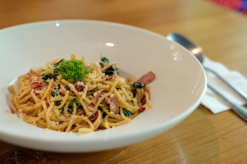 Delicious spicy spaghetti with bacon, dried chilli, basil and garlic with fork and spoon prepare side dish