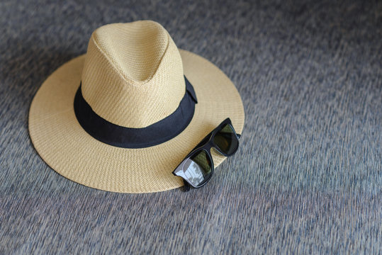 straw hat with black ribbon and sunglasses on sofa wtih free space, vacation travel in summer concept