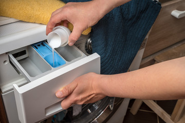 Obraz na płótnie Canvas Woman pouring washing powder into the washing machine