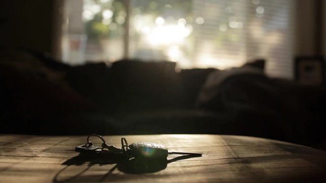 Car key and additional keys on key-ring sitting on couch in a high contrast environment in living room.