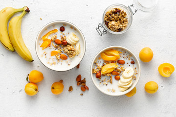 Granola breakfast with fruits, nuts, milk and peanut butter in bowl on a white background. Healthy...