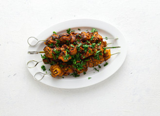 Shish kebab on skewers served on white plate on a white background top view