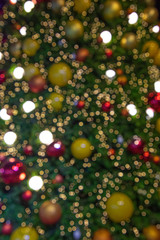 Obraz na płótnie Canvas Illuminated blurred bokeh of Christmas tree decoration with hanging lights ball.