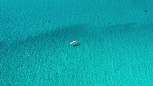 View from above, stunning aerial view of an inflatable boat with tourists on board sailing on a beautiful turquoise clear water. Spiaggia La Pelosa (Pelosa beach) Stintino, Sardinia, Italy.