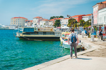 man walking by city sea quay in summer sunny day