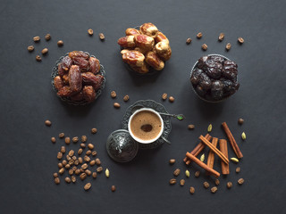 Dates and cup of Arabic coffee with cardamom on the black table.