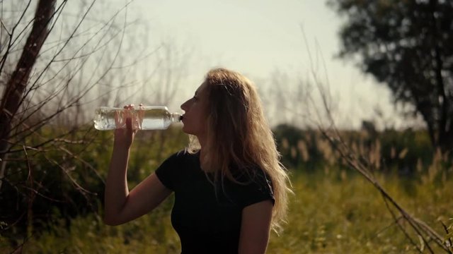Woman Drinking Water After Running.Athlete Girl Drinks Isotonic.Portrait Fitness Woman Drinking Water From Bottle.Sport Woman Drinking Water.Attractive Girl Drinks.Slow Motion Runner Drinks Water.