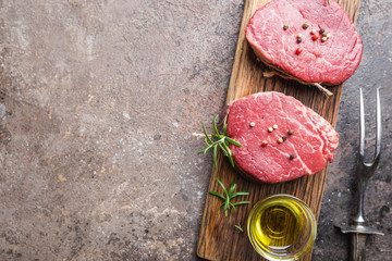 Raw marbled meat steak Filet Mignon with seasonings over stone background, top view.