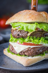 Hamburger with beef meat burger and fresh vegetables on dark background. Tasty fast food.