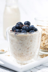 bircher muesli with fresh blueberries on white table, vertical closeup