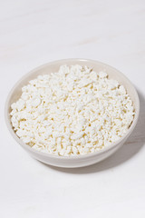 bowl of fresh farm cottage cheese on a white background, vertical