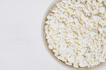 bowl of fresh farm cottage cheese on a white wooden background