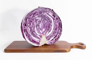 Purple cabbage cut in half on a wooden cutting board