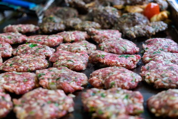 The raw meat cutlets frying at street market. Selective focus
