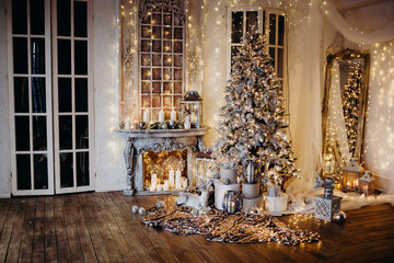 warm cozy evening in Christmas room interior design,Xmas tree decorated by lights gifts,toys, deer,candles, lanterns, garland lighting indoors fireplace.holiday.magic New year