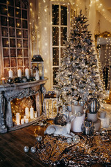 warm cozy evening in Christmas room interior design,Xmas tree decorated by lights gifts,toys, deer,candles, lanterns, garland lighting indoors fireplace.holiday.magic New year