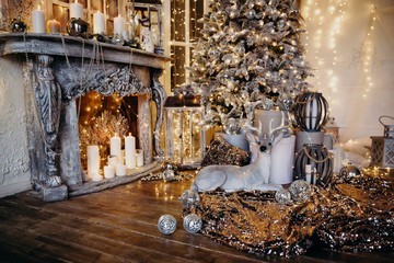 warm cozy evening in Christmas room interior design,Xmas tree decorated by lights gifts,toys, deer,candles, lanterns, garland lighting indoors fireplace.holiday.magic New year