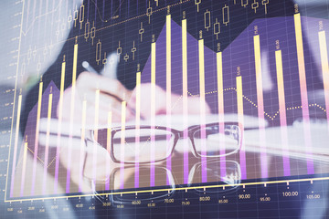 Forex chart hologram on hand taking notes background. Concept of analysis. Double exposure