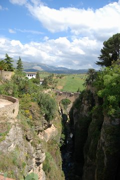 Elevated view of the old bridge crossing the ravine with views towards the countryside and mountains., Ronda, Spain.