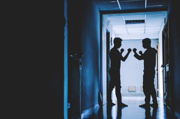 The silhouette of two young men angry conflict fighting with each other in  the old condo