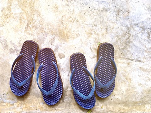 Two pairs of blue color sandal slippers arrange on cement floor for couple lover to use outside in the house. outdoor travel and holiday concept