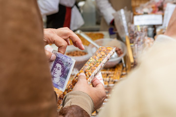 cropped women hand holding British paper money in her hand and pays an item at a market