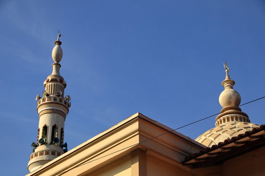 a mosque tower that resembles a nabawi mosque tower in Madina Mecca, but it is not perfectly made of shapes or altitude, with a blue sky 