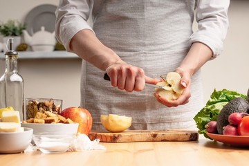 The chef prepares a vegetarian salad with the hand of a chef in the home kitchen. Light background with text area for restaurant menu design. The concept of healthy eating, cooking salad