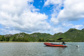 Alone fishing boats float on the sea with a blue sky and clouds background.