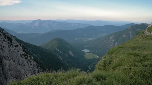 Grass Clearing On The Edge Of The Mountain Revealing Valley With Lake Surrounded By Mountain Peaks Push In Pan Down Shot, Mangart Bovec, Slovenia