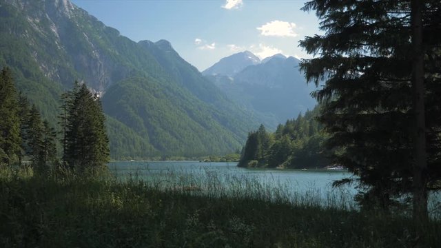 Grass Clearing In Front Of Mountain Lake Surrounded By Mountains Left Truck Shot, Lago Del Predil, Italy