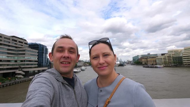 Couple taking selfie with a view of Thames river and the Shard skyscraper in London in 4k slow motion 60fps