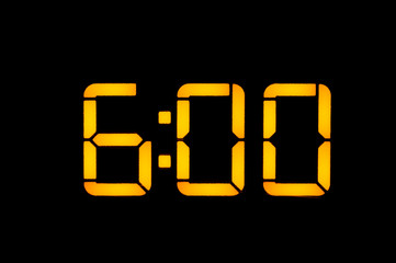 Electronic digital clock with yellow numbers on a black background shows the time of six zero zero...