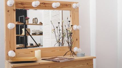 Table with makeup products and mirror near white wall. Dressing room interior. Modern interior in the girls bedroom