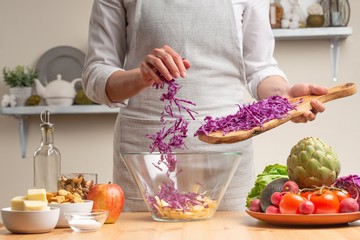Chef cooks, chops cabbage, stir, in the process of a vegetarian salad with the hand of the chef in the home kitchen. Light background for restaurant menu design, menu, recipe book
