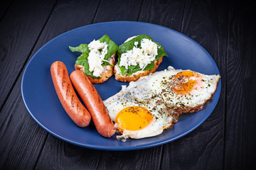 Fried eggs with sausages, cream cheese and ham. Food for breakfast. Fresh, homemade food for family. Homemade delicious american breakfast with sunny side up fried egg