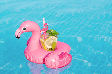 Fresh coctail mojito on inflatable pink flamingo toy at swimming pool. Vacation concept.