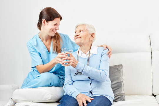 Nursing assistant gives senior citizen a glass of water