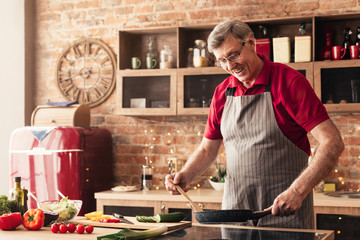 Caring senior man preparing breakfast at kitchen