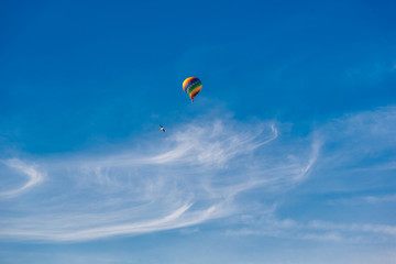 Balloon flying through the blue sky among the clouds. Freedom, adventure, loneliness. Birds are stolen around