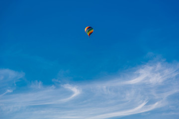 Fototapeta na wymiar Balloon flying through the blue sky among the clouds. Freedom, adventure, loneliness.