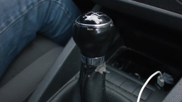 Close up of a gear shift. Hand of a woman grabs the shift and changes gear.