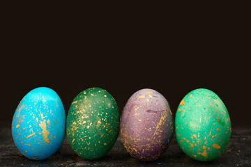 Easter dyed eggs on black background. Luster shiny golden colors. Modern and contemporary style. Copy space concept.