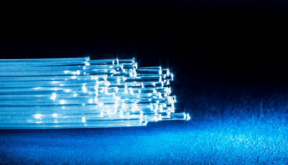 Bundle of optical fibers with lights in the ends. Blue background.
