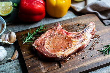 Raw pork chop steak with BBQ sauce on top on wooden background