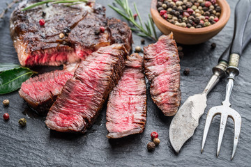 Medium rare Ribeye steak with herbs on graphite board.