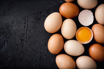 Organic chicken eggs on top of dark wooden background.