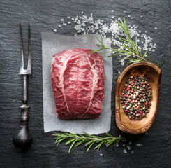 The top blade steak or beef steak on the graphite board with herbs and spices.